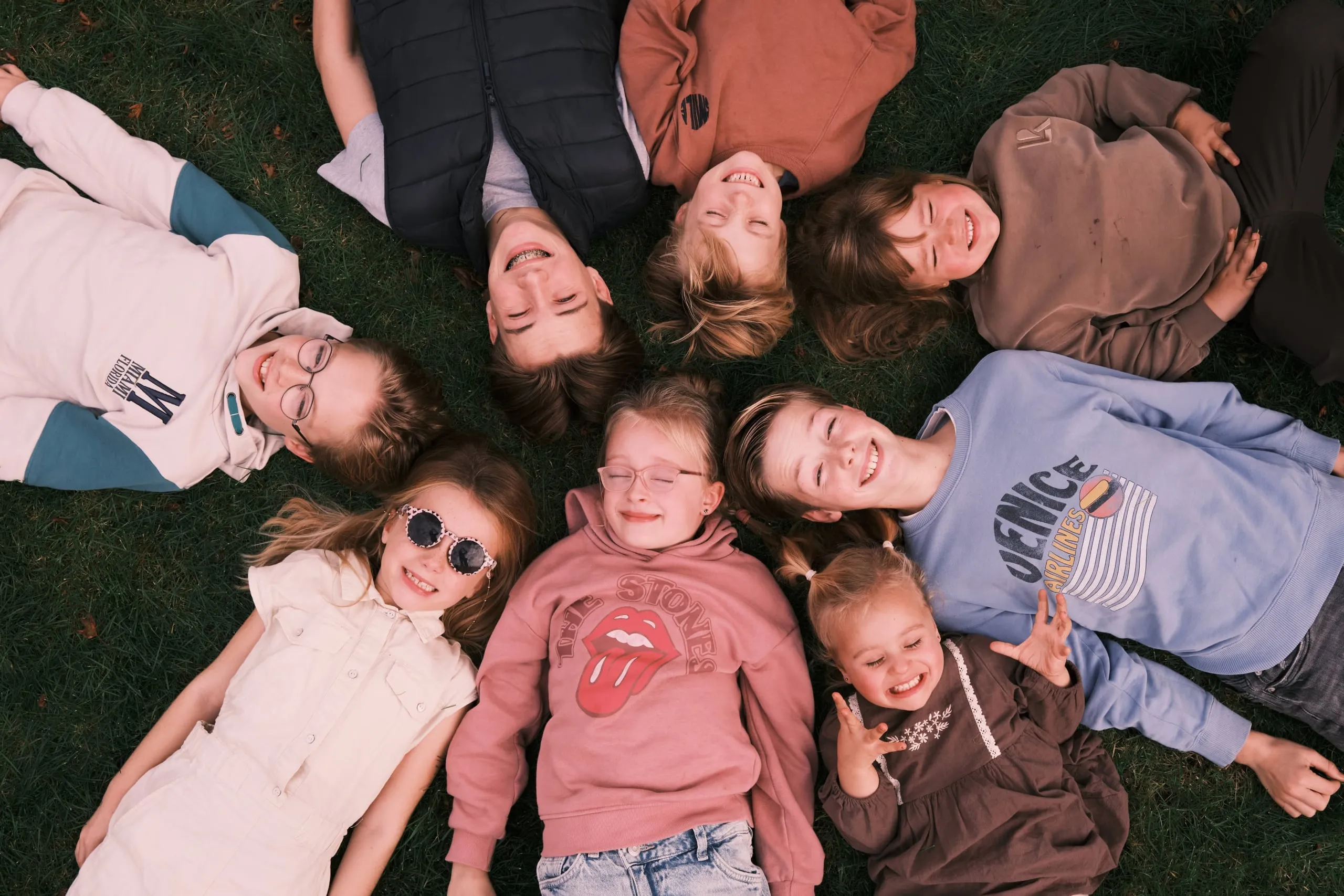 Voorbeeld van Kinderen: Een groep kinderen op het strand en in het gras: lachen, knuffelen en samen op de foto.
